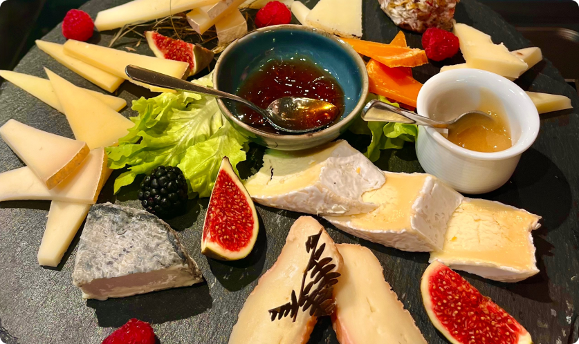 picture of french cheese, marmelade, and fruits on a plater